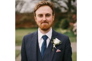 Josh Kendall wears a suit and smiles at the camera