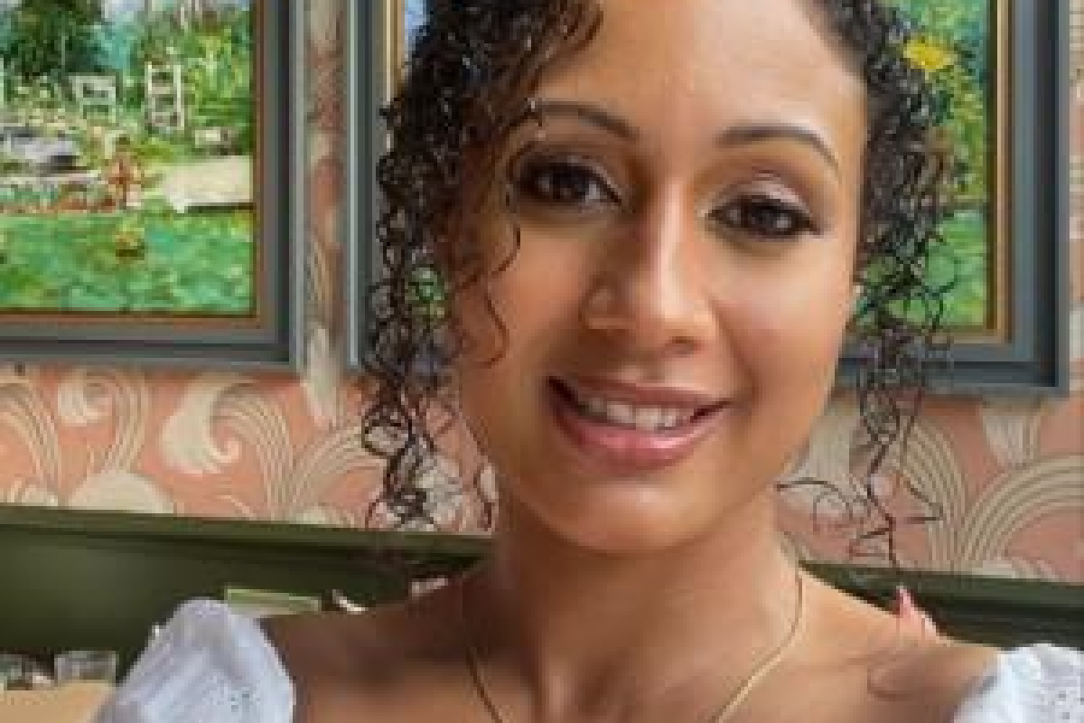 Simone smiling with a white top and small gold chain